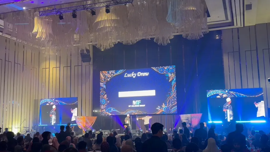 A ballroom audience watching a live lucky draw on the main stage screens at a corporate gala.